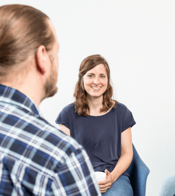 Rückenansicht eines Trainers, der vor einer sitzenden Frau steht